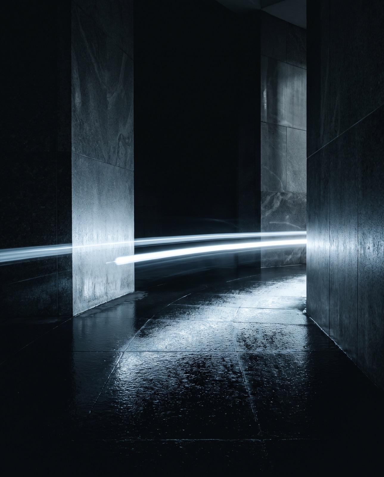 A single streak of light passing through a dark stone corridor